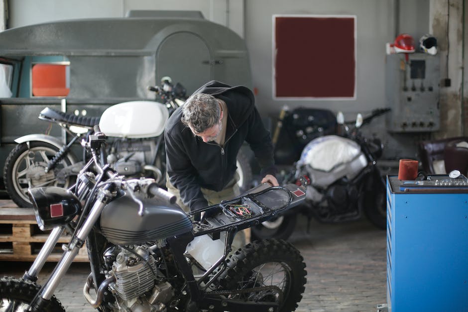 An image showing a person using a portable motorcycle diagnostic tool in a field for troubleshooting a bike.